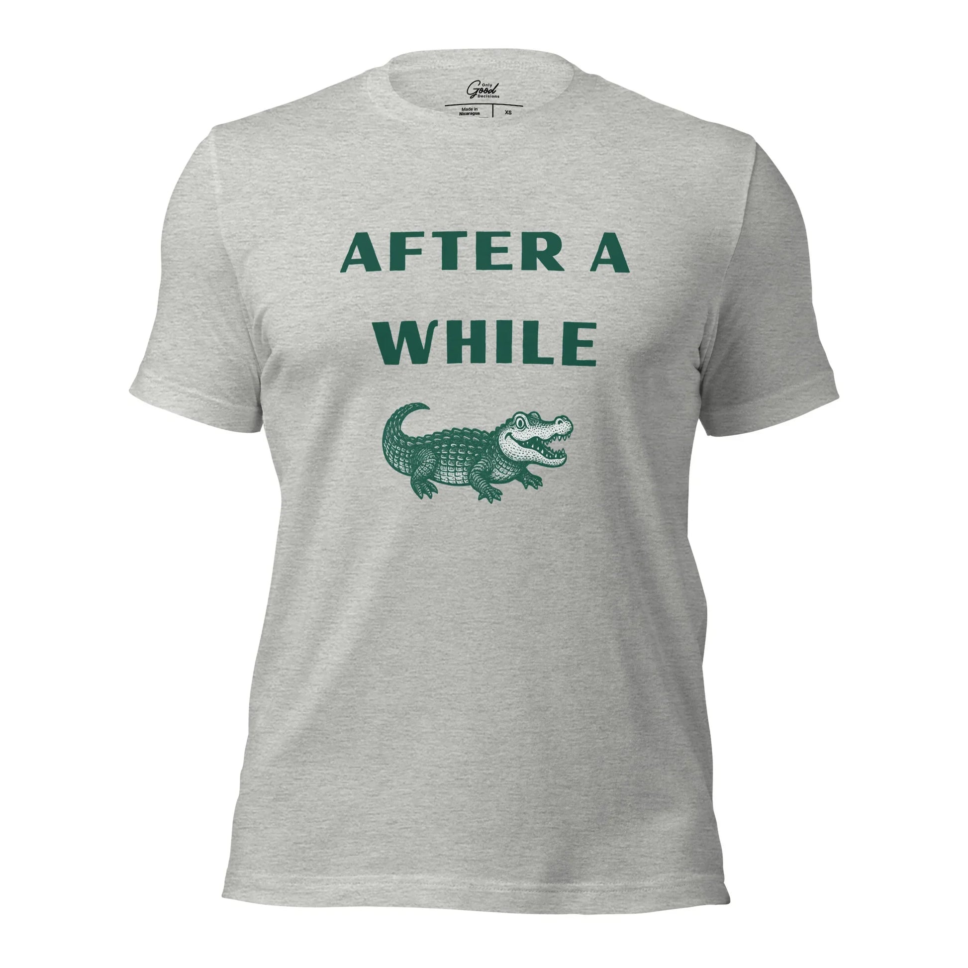 Athletic Heather After A While Crocodile classic idiom t-shirt featuring the text "AFTER A WHILE" in green above an illustration of a crocodile.