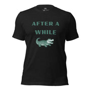 Black Heather After A While Crocodile classic idiom t-shirt featuring the text "AFTER A WHILE" in green above an illustration of a crocodile.